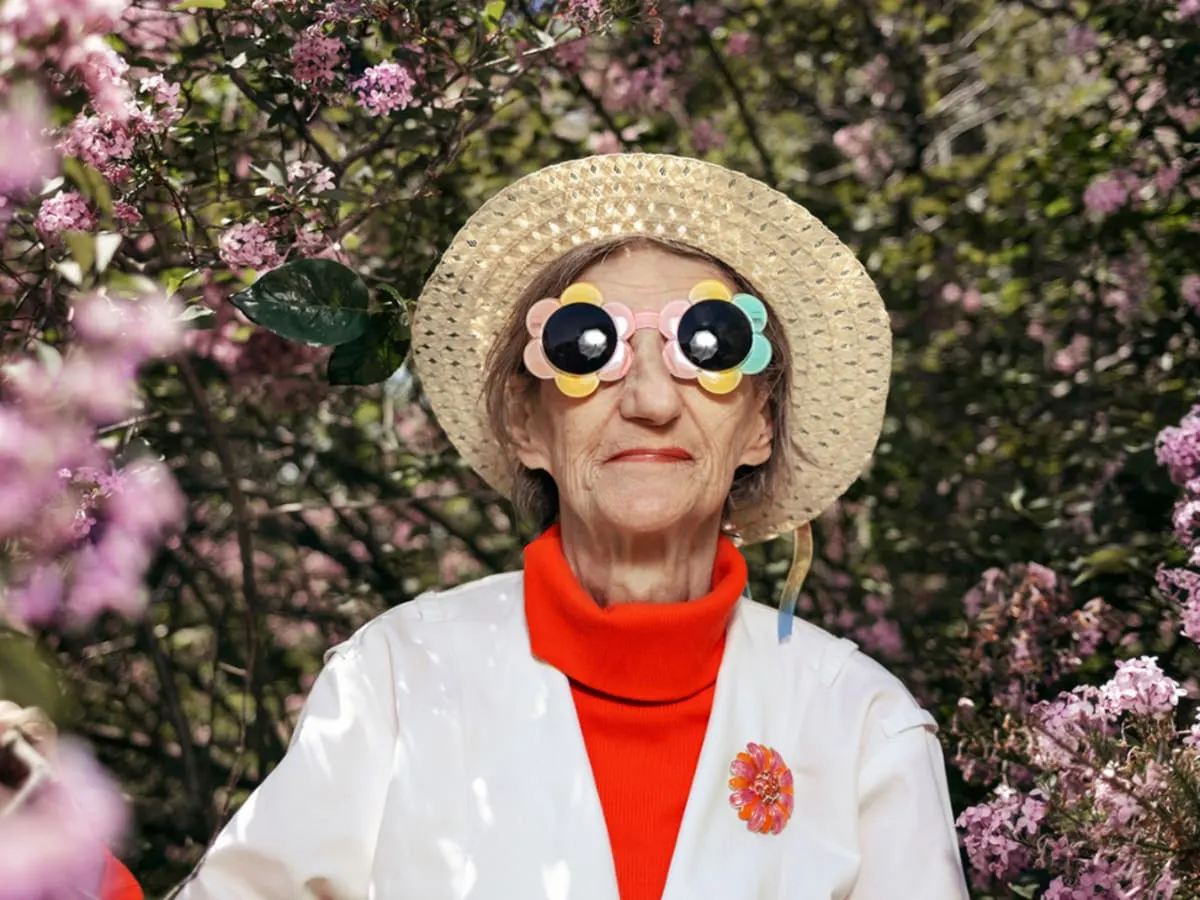 Une dame ayant un chapeau et des lunettes de soleil en forme de fleurs.