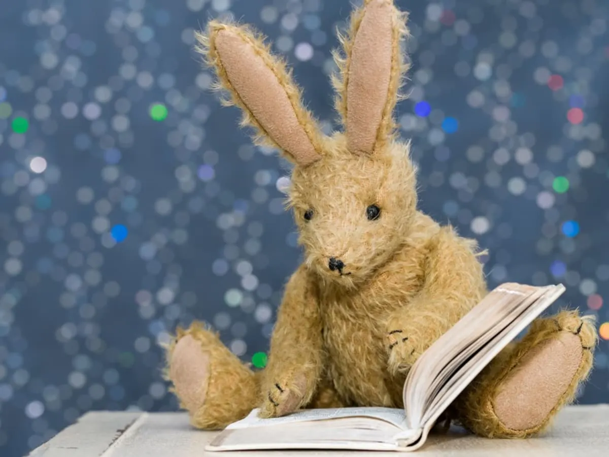 Lapin en peluche qui lit un livre.