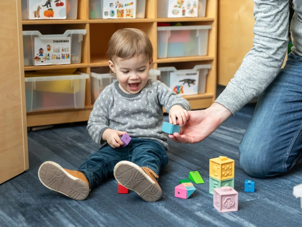 Accompagné de son parent, un tout-petit joue avec des jouets à la bibliothèque Frontenac.