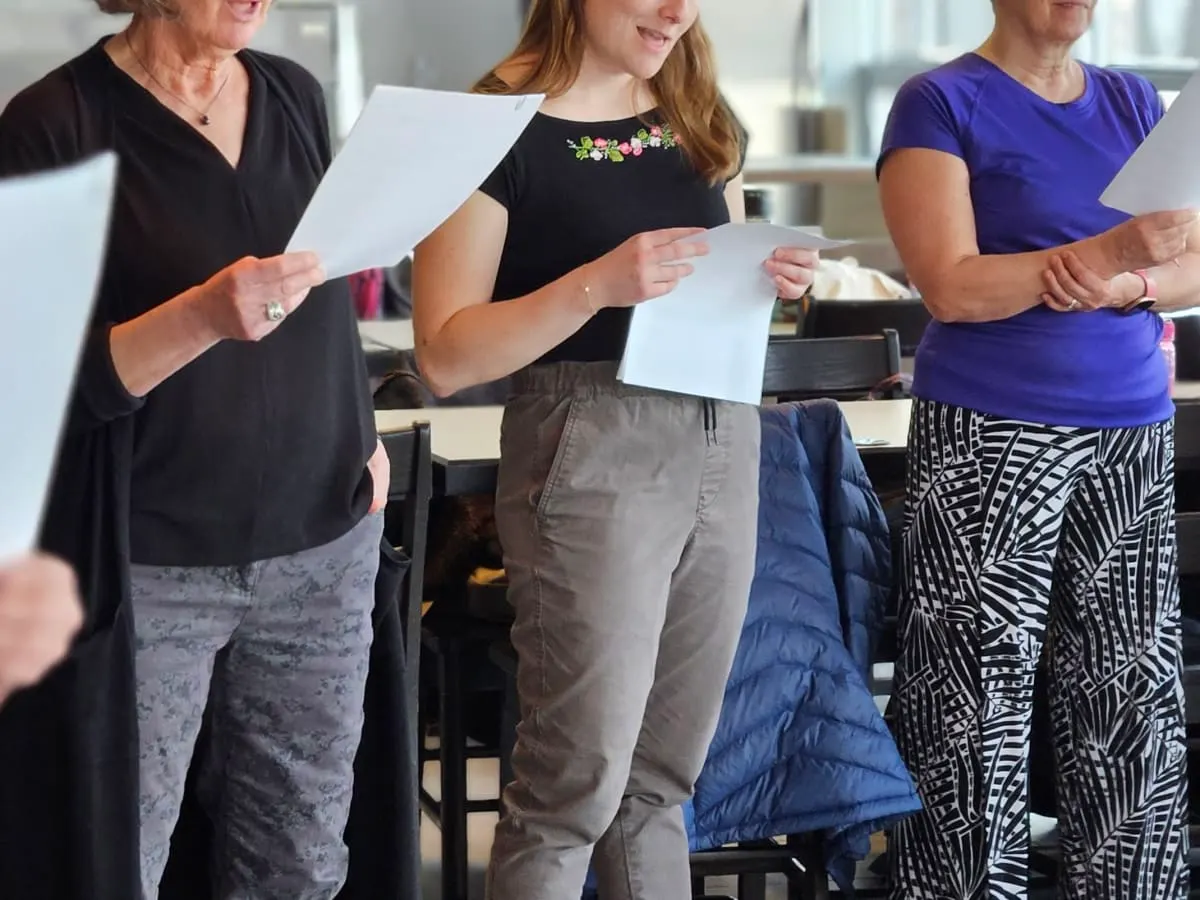 Photo de plusieurs femmes blanches qui tiennent des papiers blanc en chantant