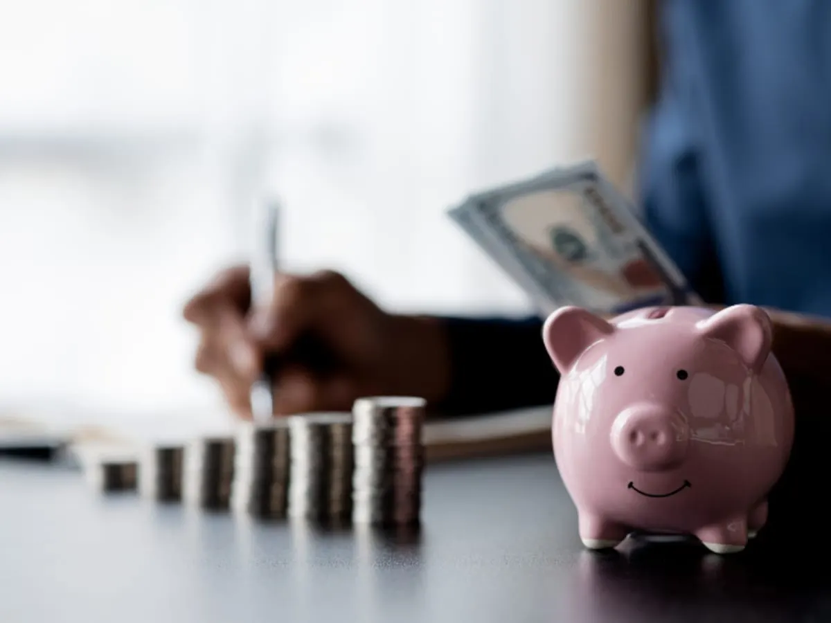 Un cochon-tirelire et des piles de monnaie sur un bureau.