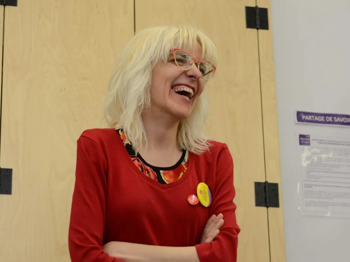 Une femme debout qui éclate de rire.