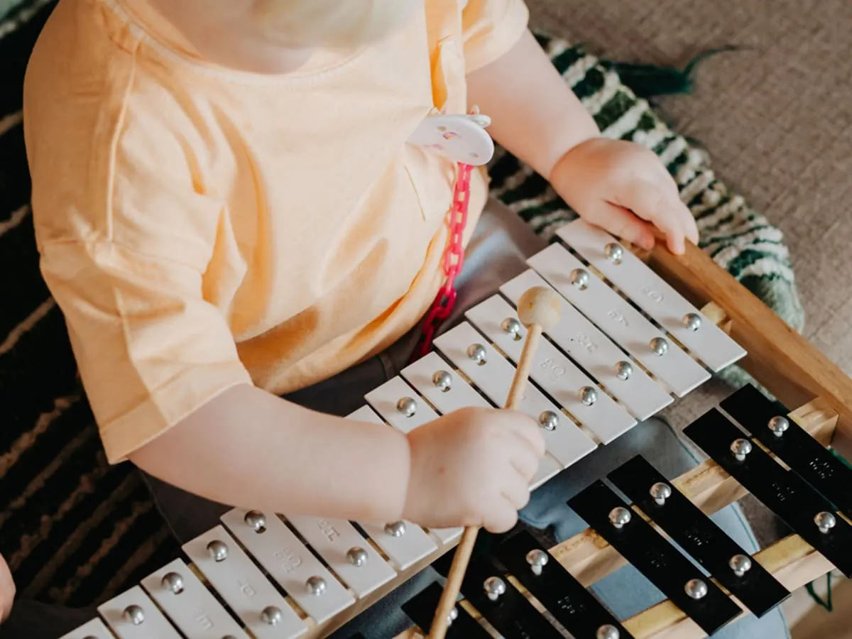 Un enfant joue du métallophone avec une baguette.