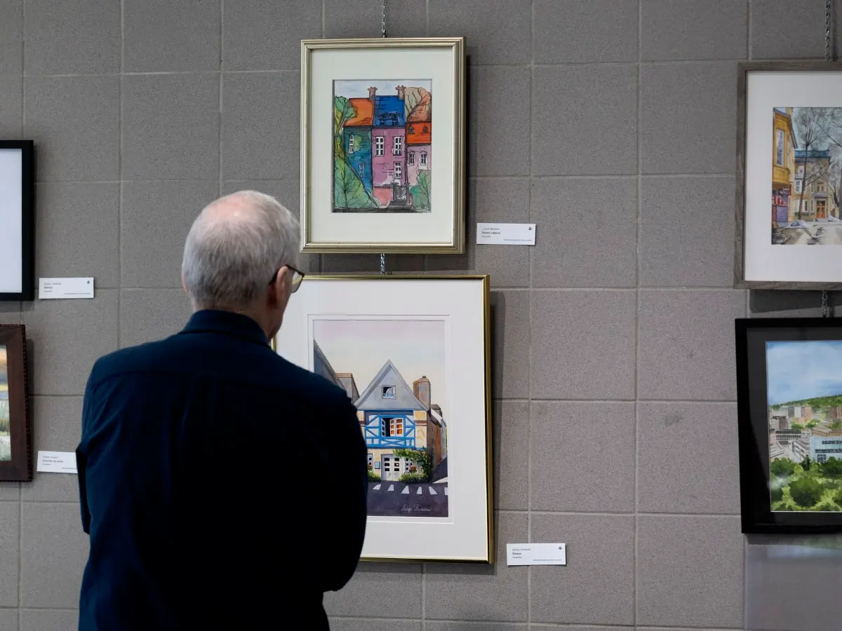 Une personne de dos admire des oeuvres d'aquarelle